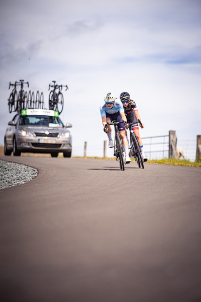 Two people on bikes race each other down the road.