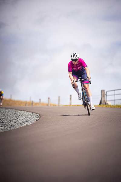 A cyclist wearing a pink jersey and riding a blue bike.