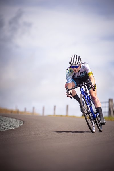 A bicycle racer is seen wearing a helmet as they race down the road.