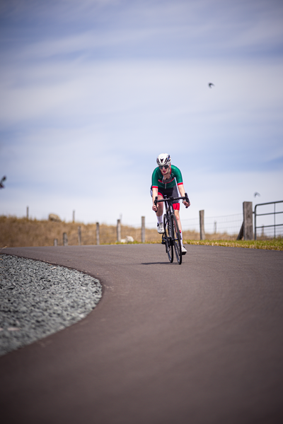 A person riding a bike, wearing a green and red shirt.