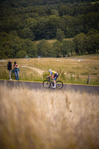 A cyclist with a red and black jersey on is participating in a cycling event.