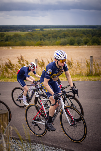 Two women are riding bikes in a field on a cloudy day.