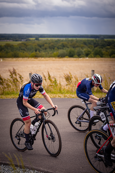 Two women on their bikes wearing helmets as they race.