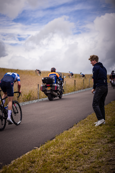 Bike race in a field with people on bikes including a person wearing an orange and blue shirt.