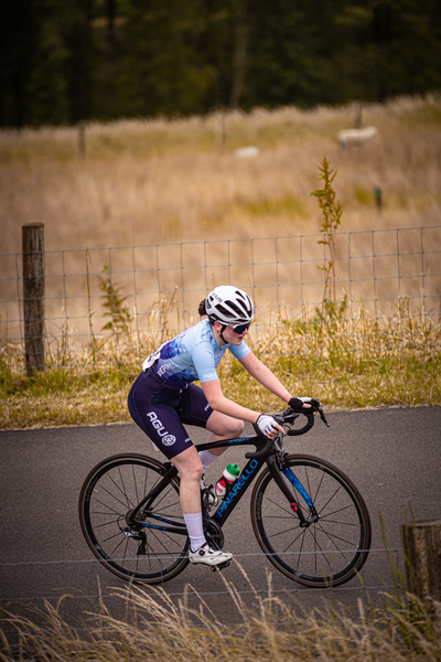 A young girl is wearing a blue and white shirt while riding her bicycle.