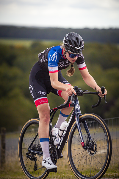 A woman wearing a black, red and white outfit riding a bike.