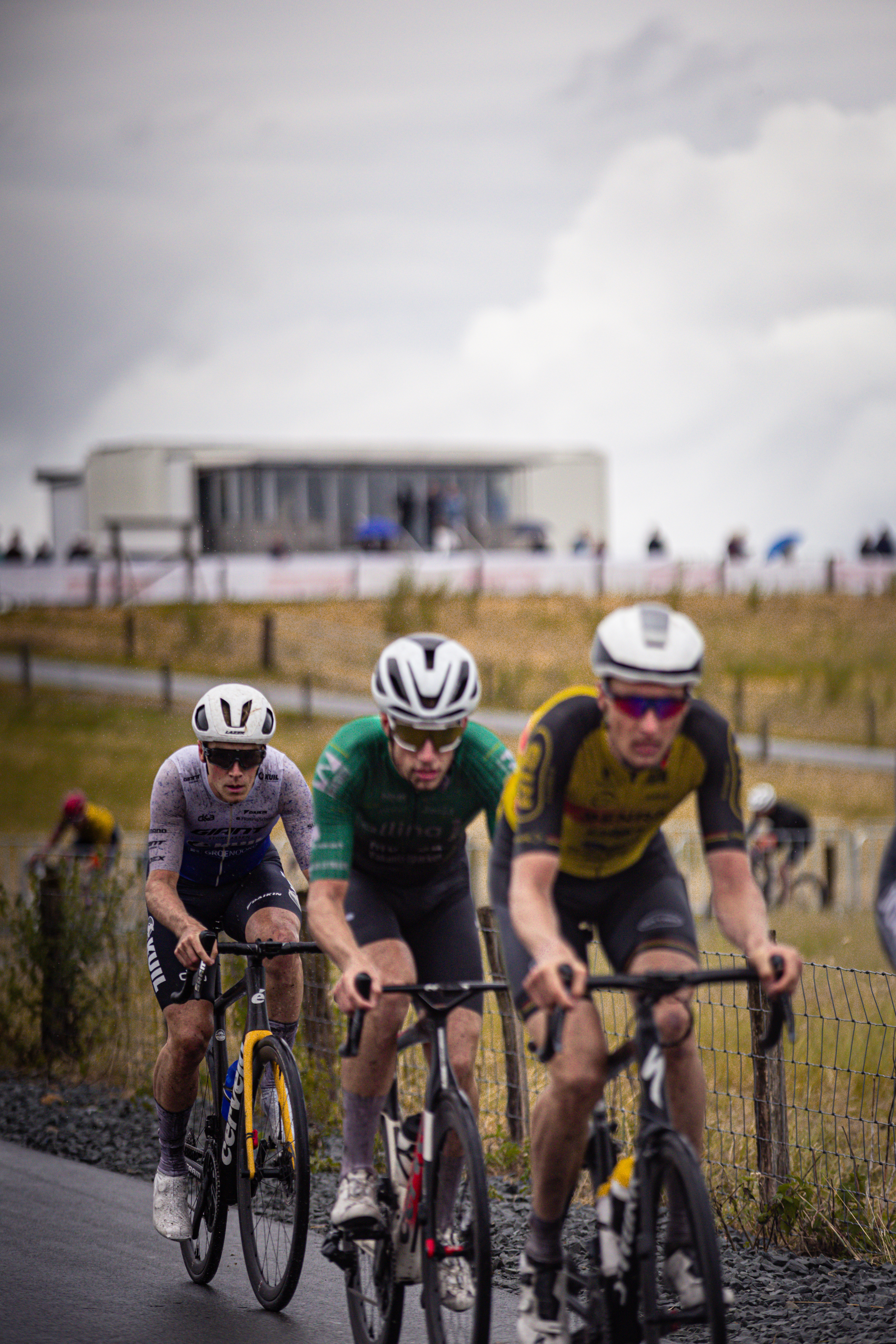 A group of bicyclists, including number 7 and 3, are racing in the Nederlands Kampioenschap.