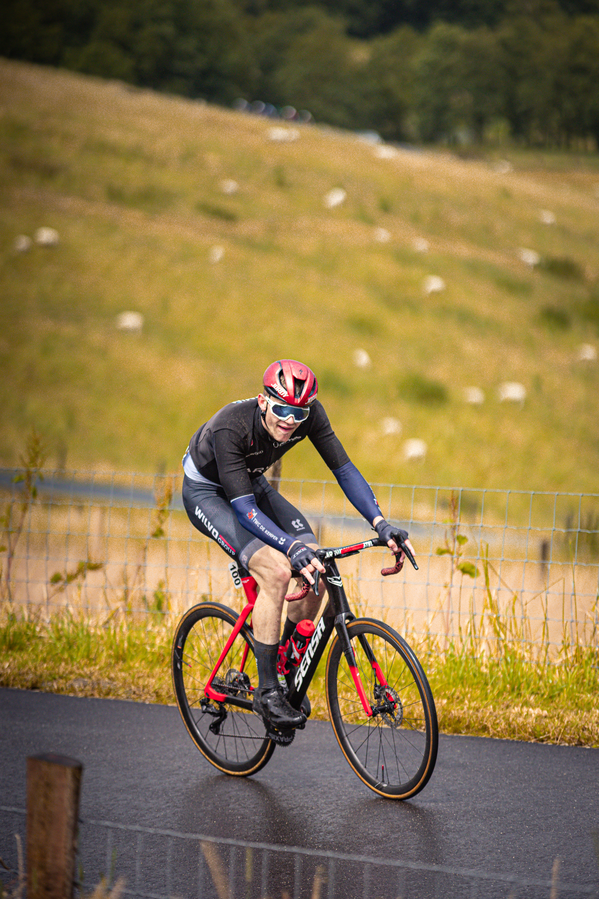 A person on a bike with red lettering is wearing black, blue and white clothing.