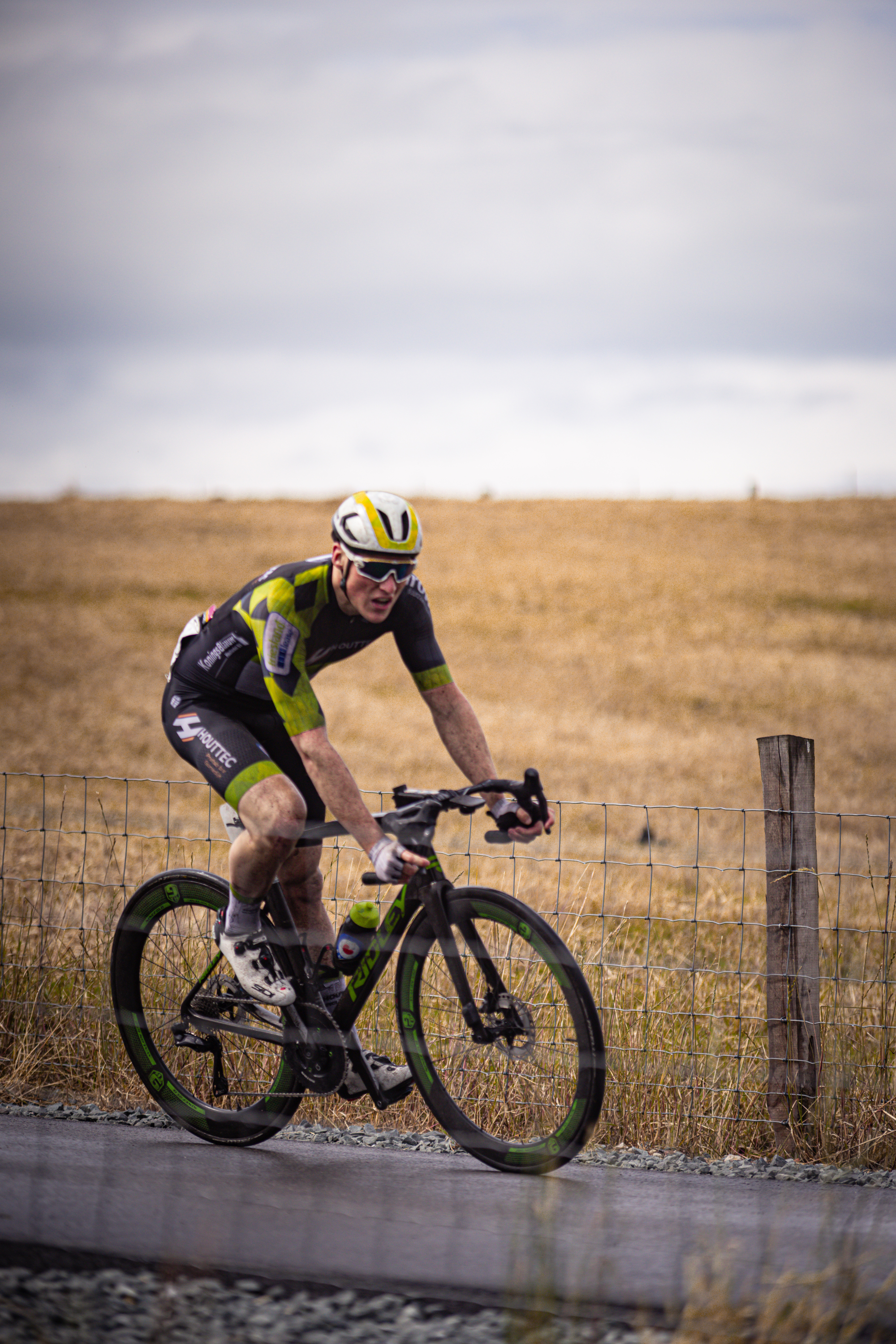 A man on a bicycle wearing black and yellow and a helmet.