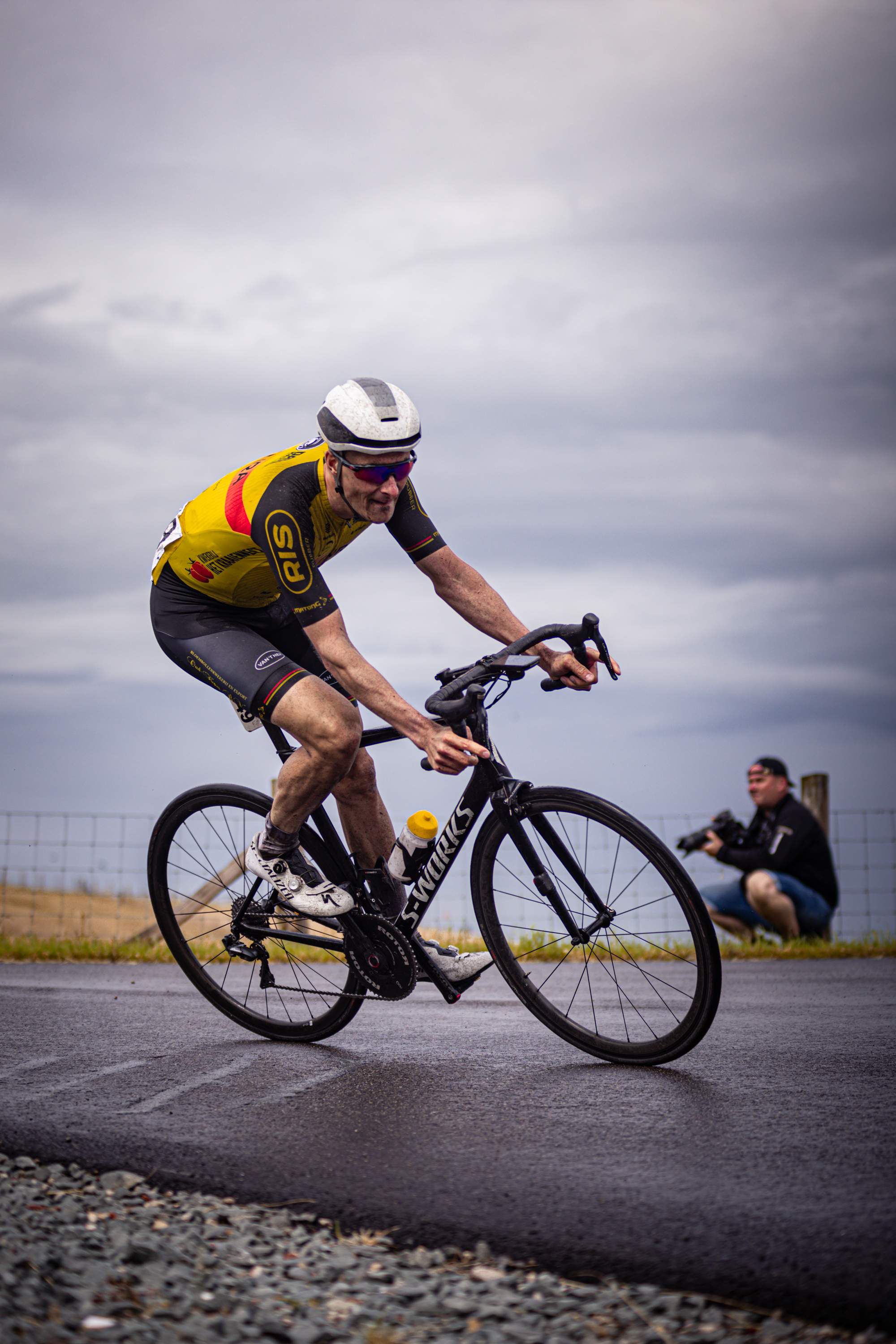 A man in a yellow and black uniform riding his bicycle.