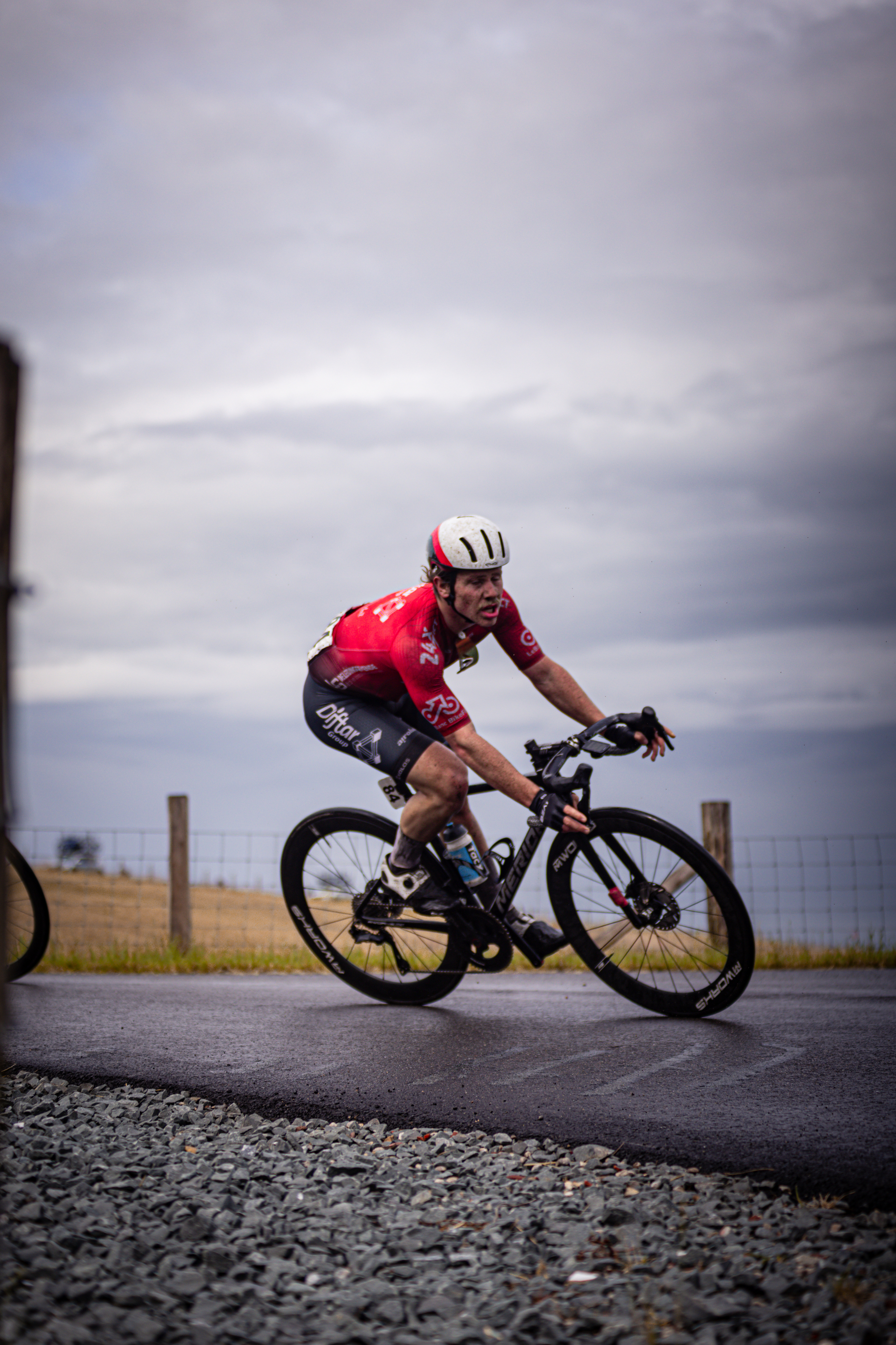 A man wearing a red and white shirt rides his bicycle down the road.