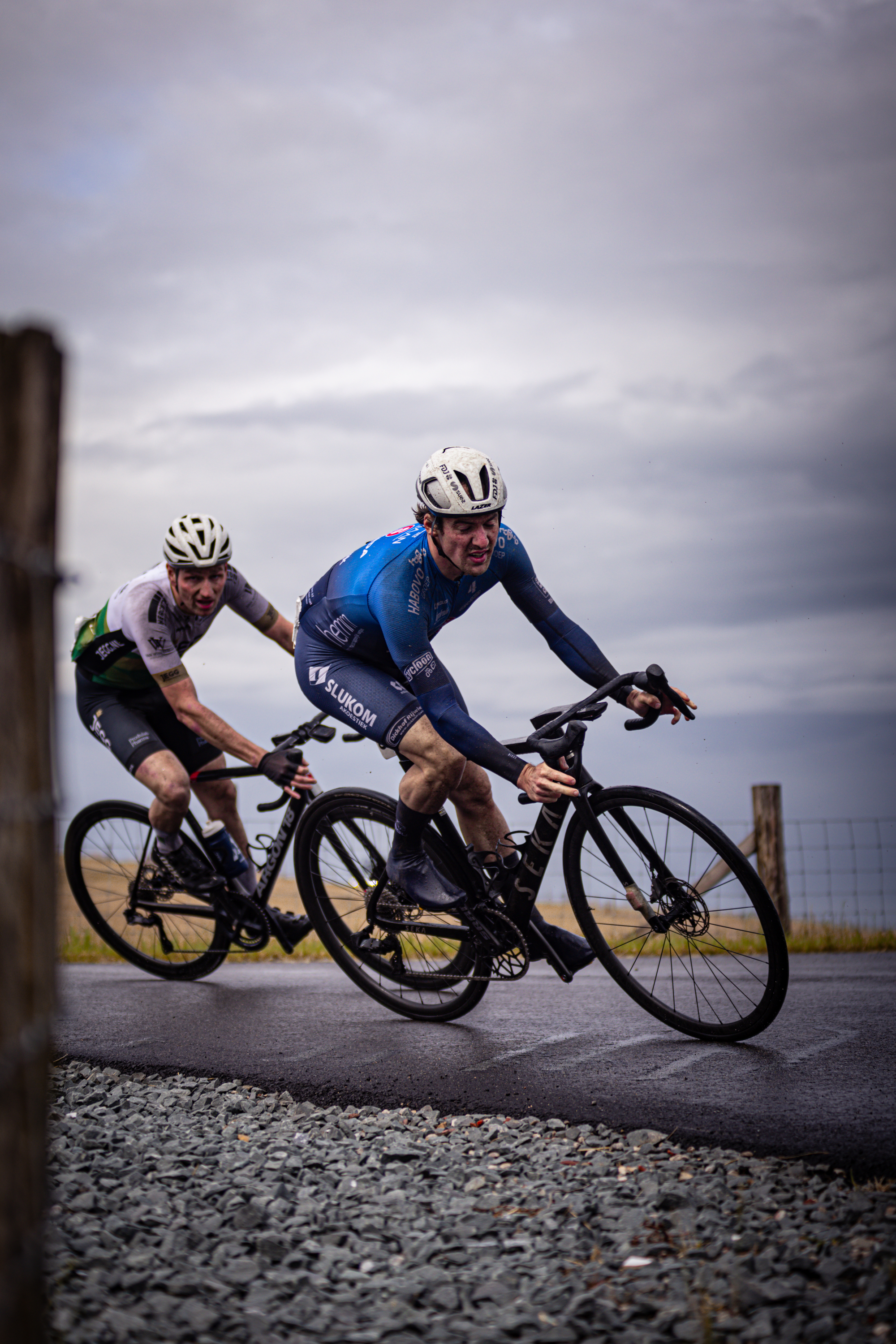 Two men riding bikes, with one wearing a blue and white jersey.