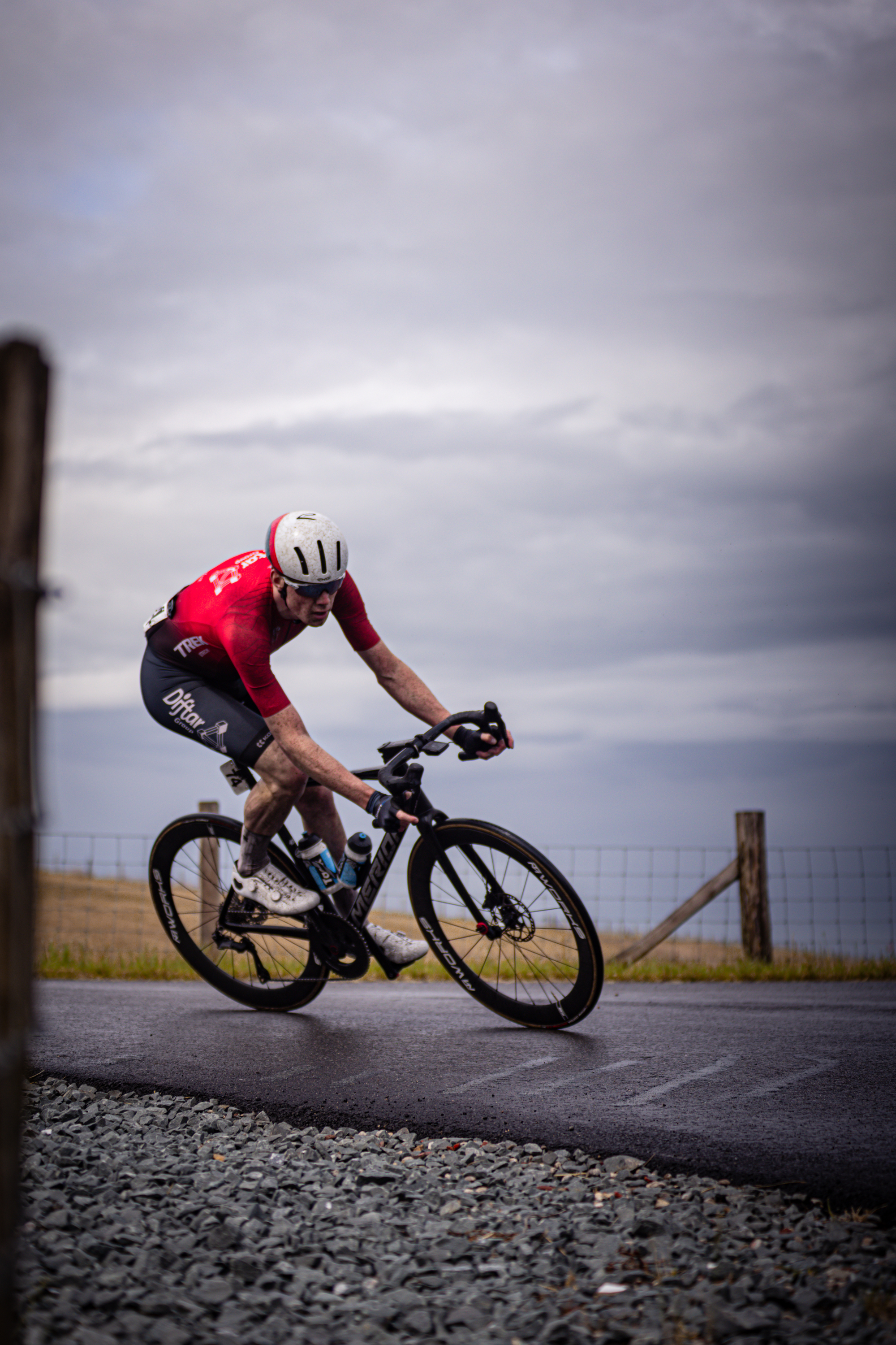 A man wearing a red shirt is riding his bicycle on the side of a road.