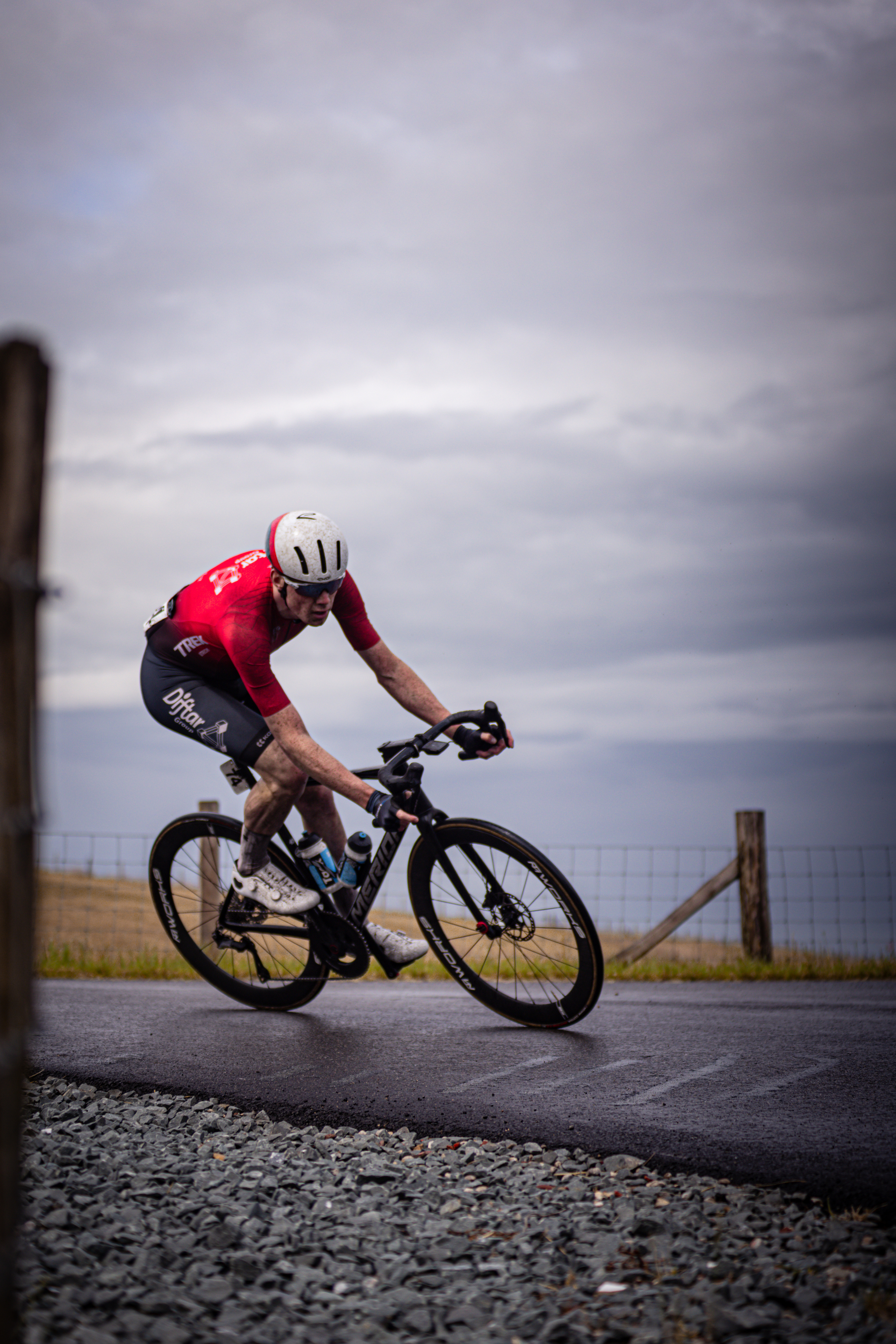 A man wearing a red shirt is riding his bicycle on the side of a road.