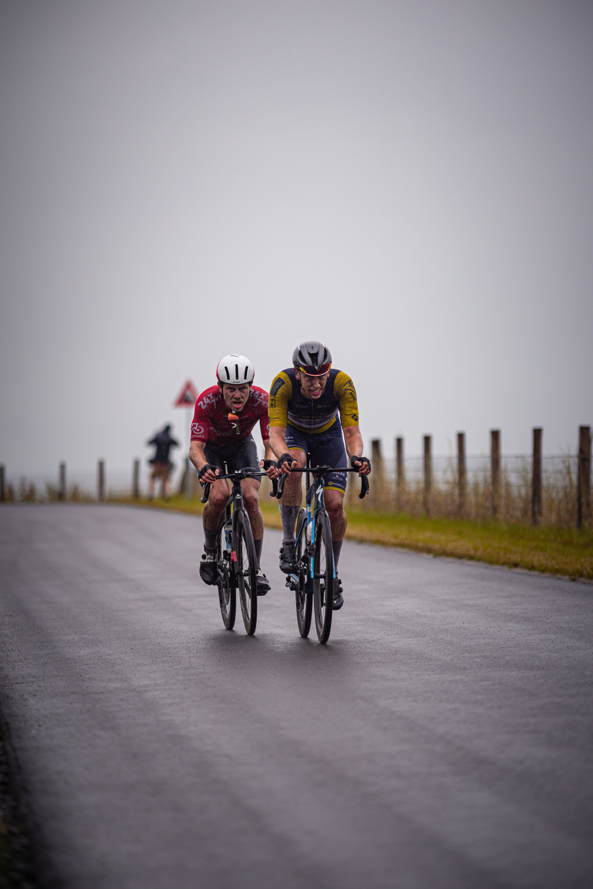 Two cyclists racing down a road with one in a yellow jersey.