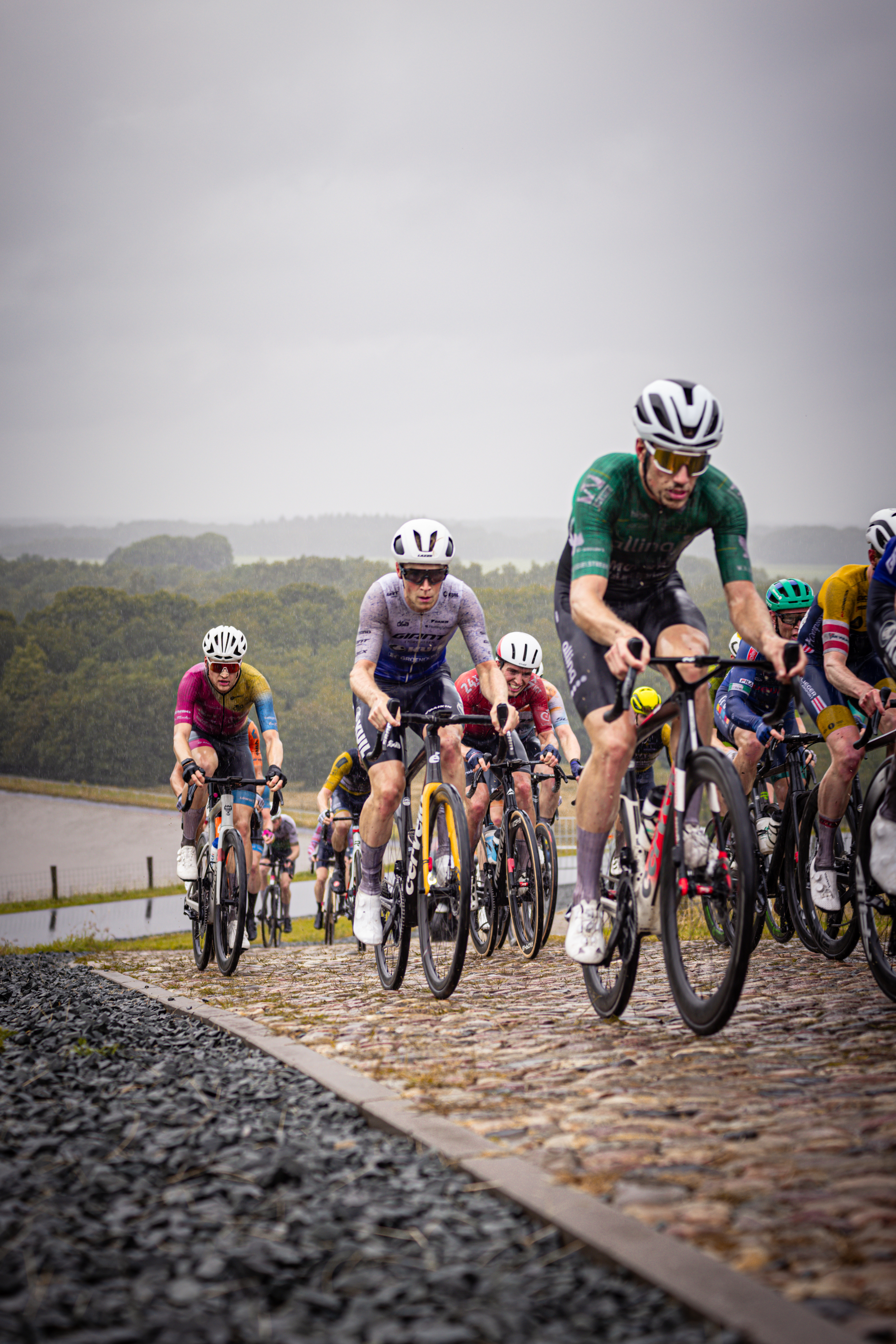 A group of people riding bicycles and racing on a cobblestone road.