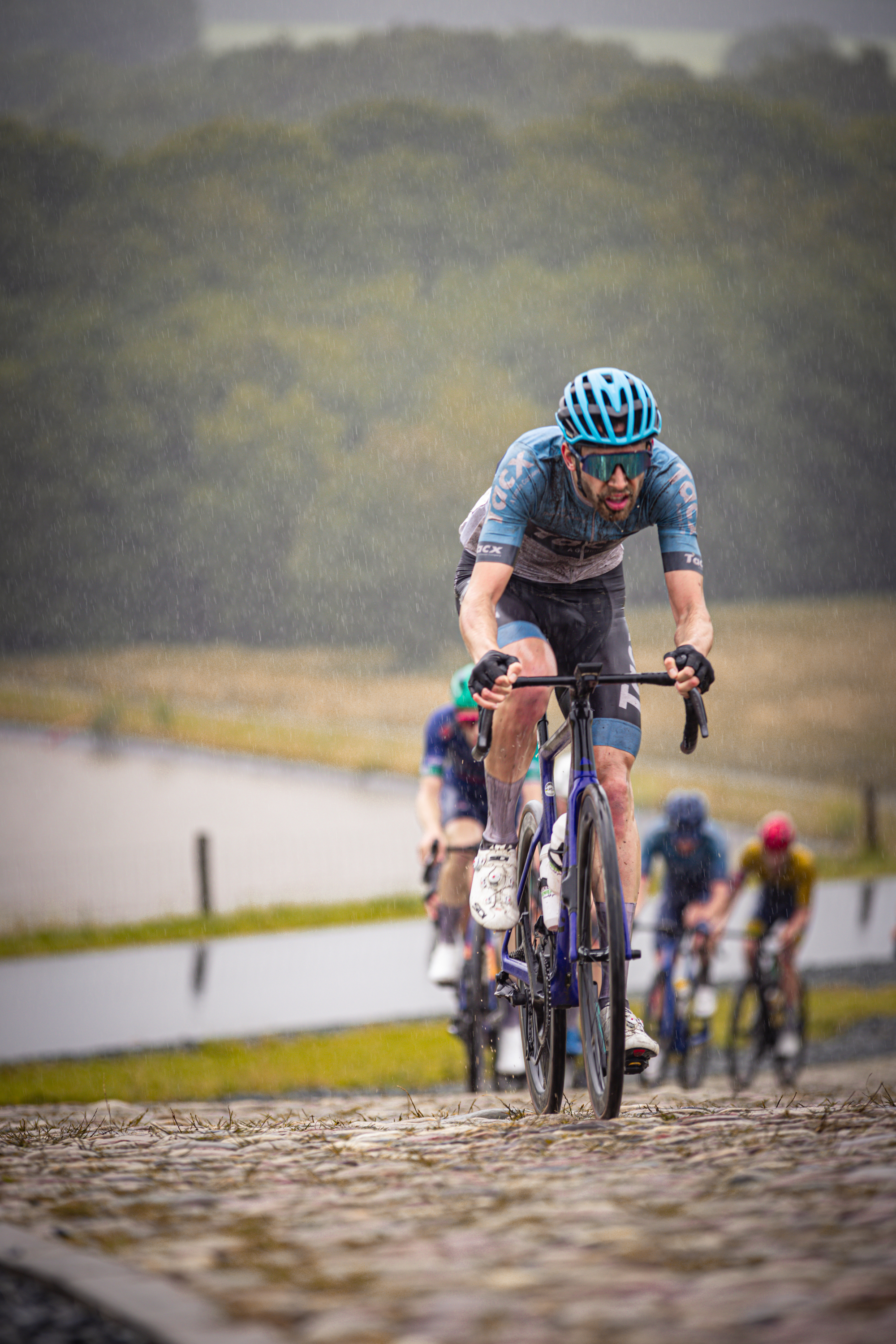 A group of men are riding bikes down a cobblestone path.