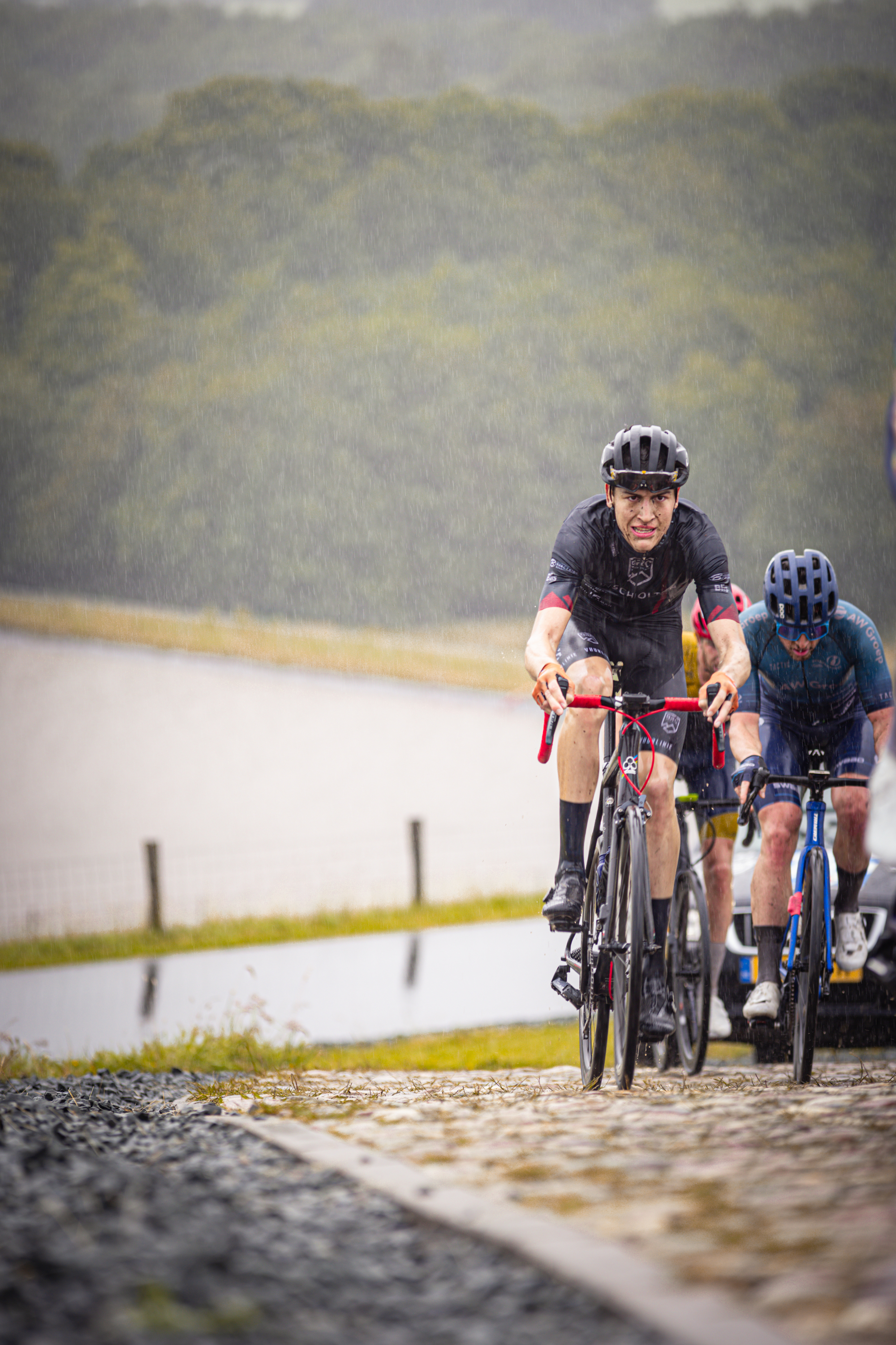 Two men riding bicycles in a race on a cobblestone road.