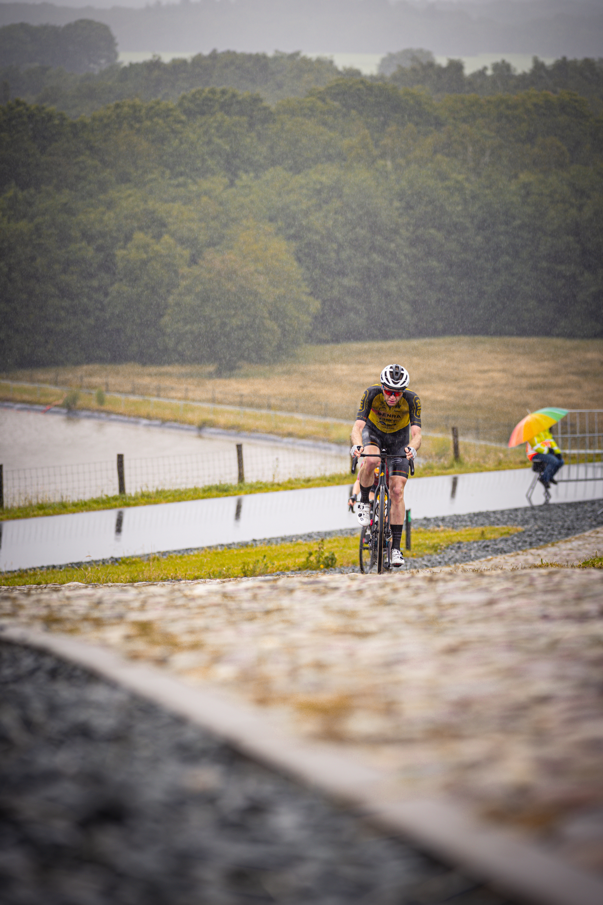 Two cyclists are riding on a track, one of which is wearing a white helmet.