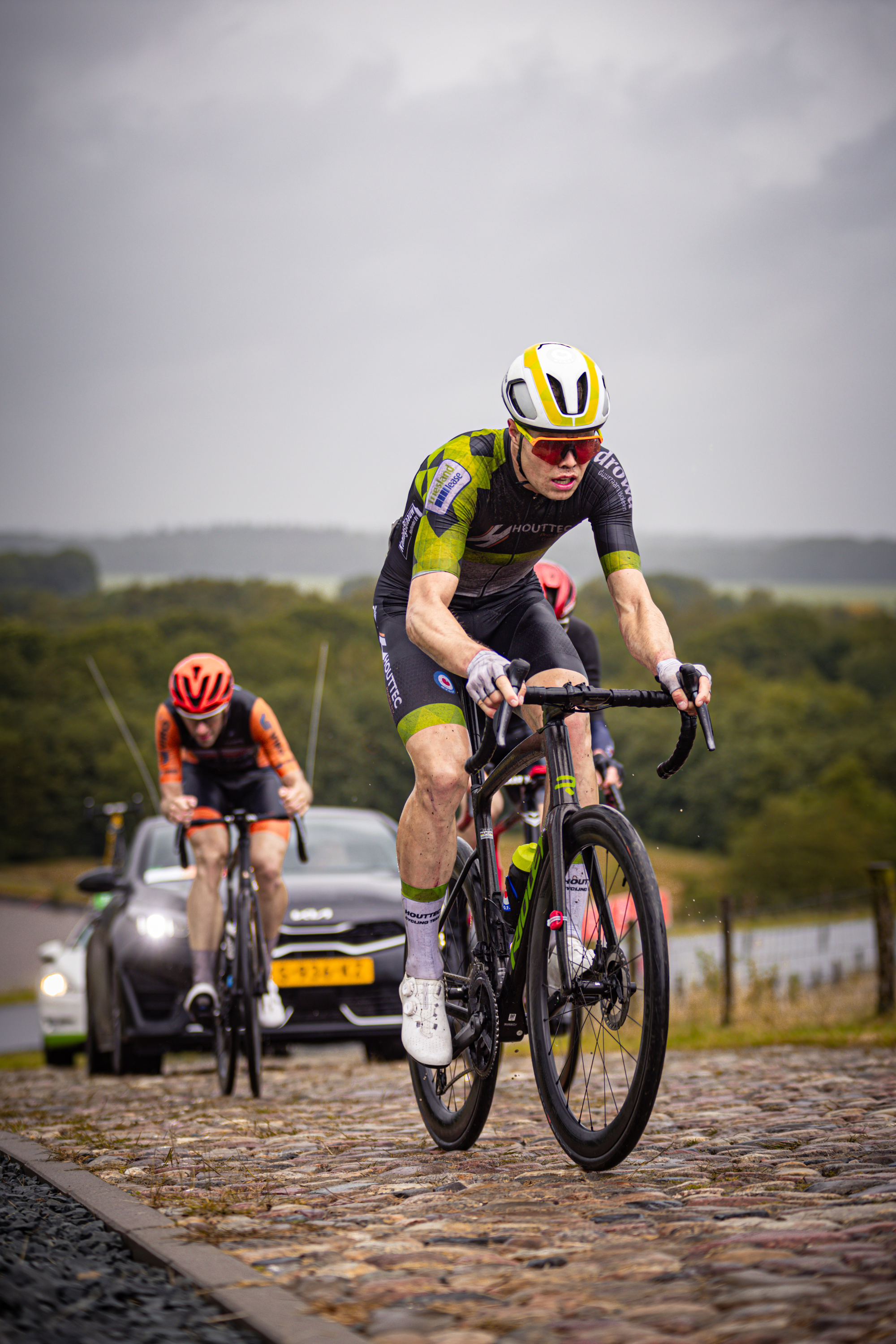 Two cyclists, one in a yellow and black jersey with 2024 on it.