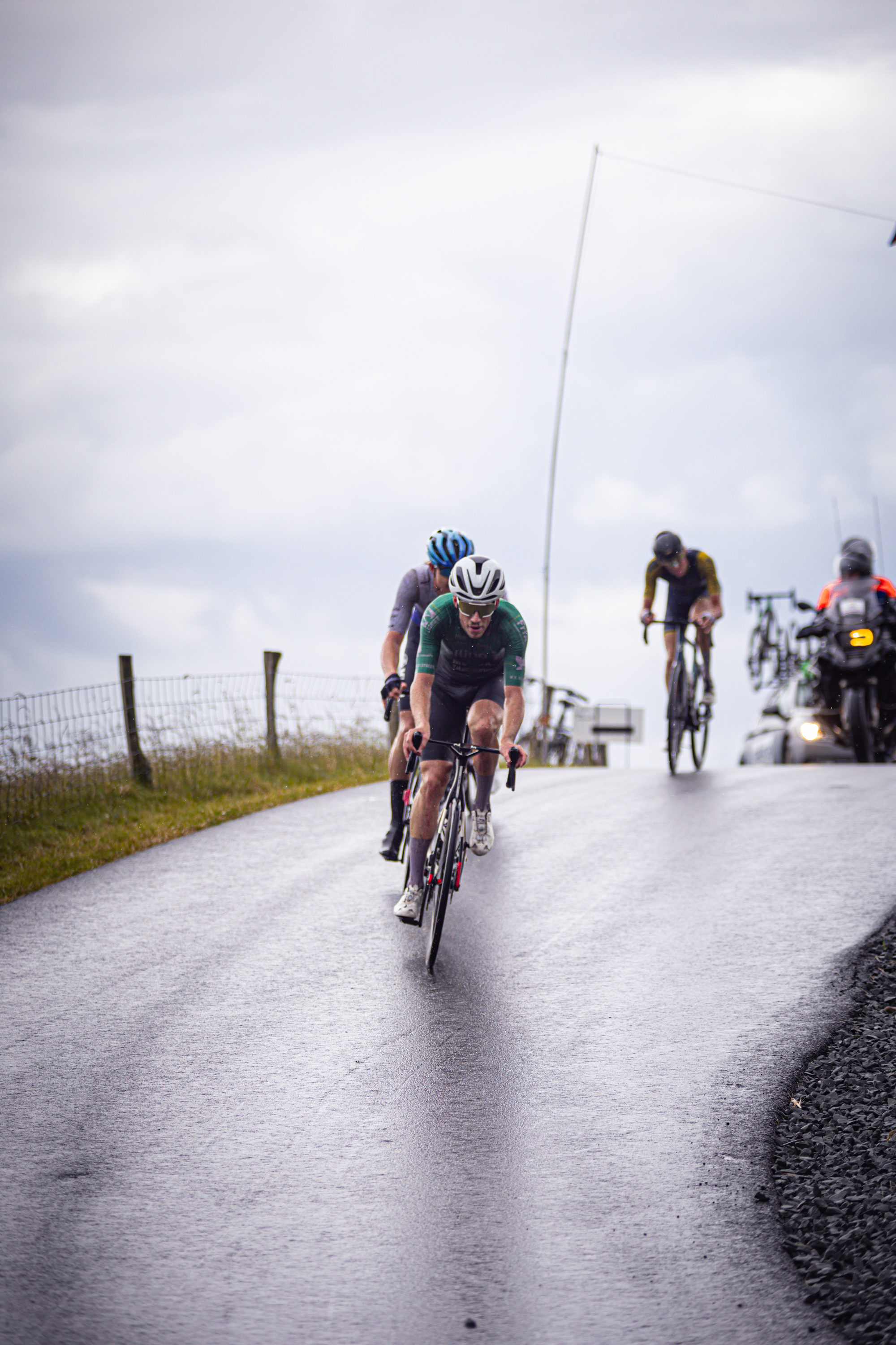 Three cyclists are on a wet road in the middle of a race.