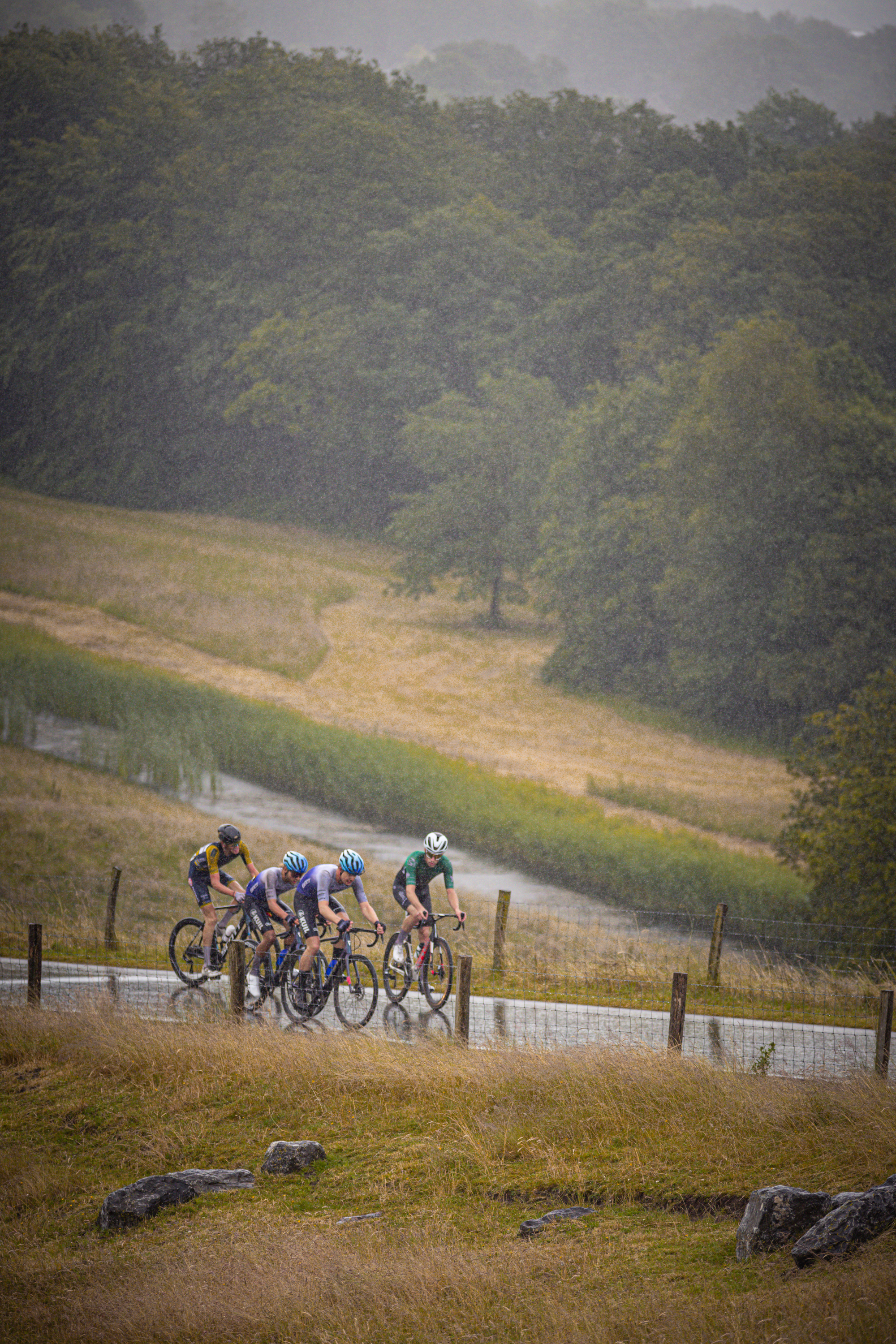 A group of cyclists on a rain-soaked track in the Netherlands during a bicycle race.