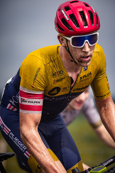 A cyclist in a yellow and blue jersey with the words Plus Energy on it.