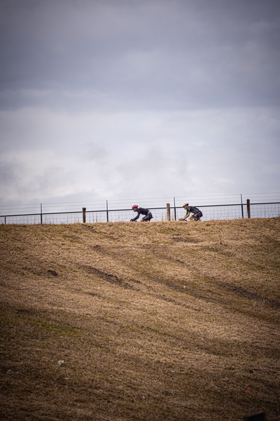 Three cyclists wearing helmets are riding down a hill.