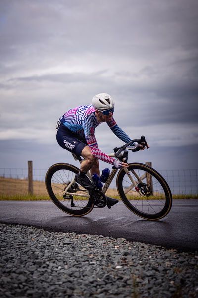 A man wearing a colorful jersey is riding his bike down the street.