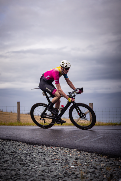 The cyclist is riding a black bike wearing a pink shirt.