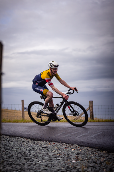 A cyclist in a blue and yellow outfit riding a black bicycle.