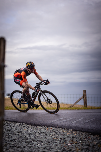 A man is riding his bike on the road and he has a helmet.