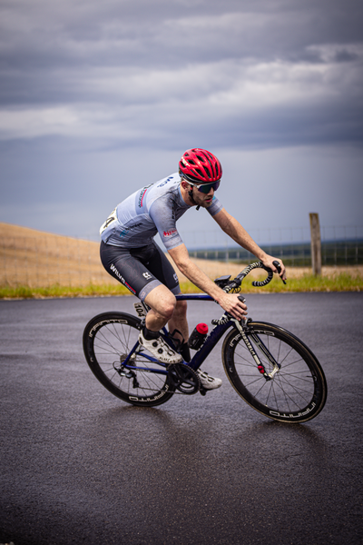 A man wearing a red helmet and riding a blue bicycle.