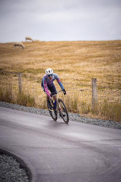 A biker wearing a helmet and riding a bike on a road.