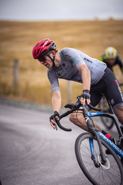 A man in a helmet is on the road with his bicycle during a cycling race.