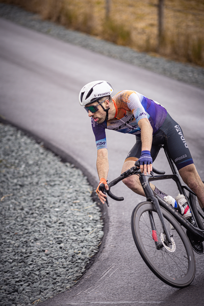 A man in a cycling race is wearing a white and purple jersey.