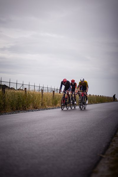 Three bikers wearing racing helmets compete in the Netherlands Championship of Cycling.