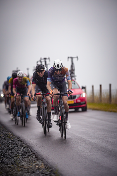 A group of cyclists racing down a road with one wearing a white number 2.