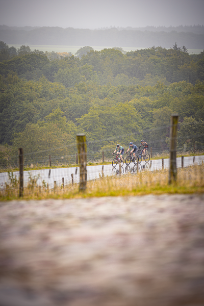 Three cyclists race on a dirt track in the Nederlands Kampioenschap.