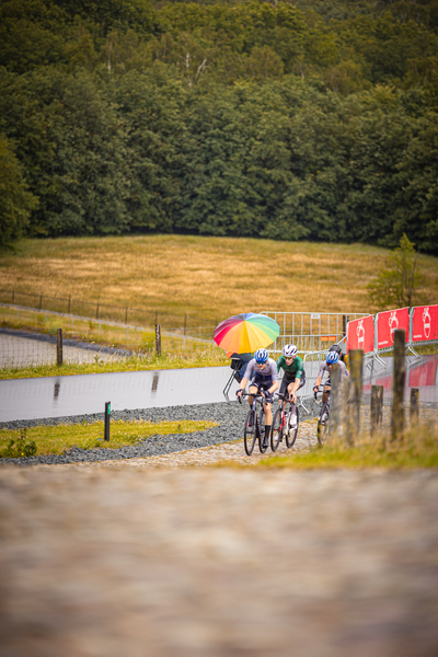 A group of cyclists race on a track under an open sky.