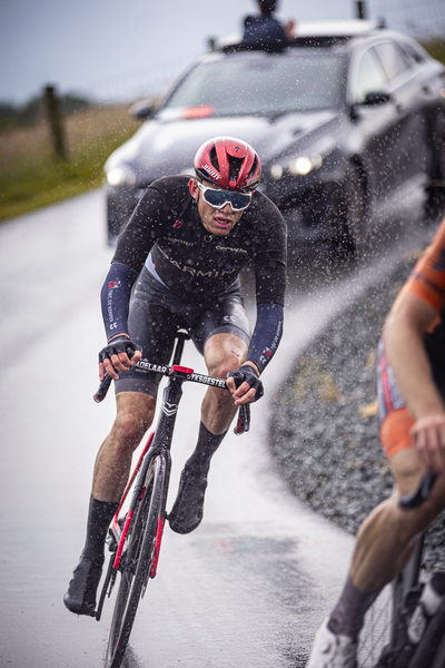 A man in a black wetsuit on a bicycle with the words Nederlands Kampioenschap 2024 Wielrennen Mannen Elite ZC on his uniform.