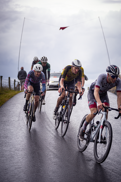 A group of athletes are riding their bikes down a road.