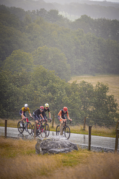 Four men are racing on their bicycles during a rainstorm.