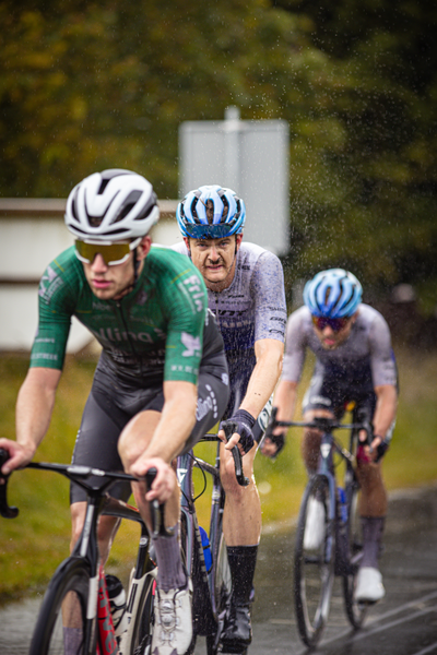 Three men are racing a bike race sponsored by Netherland.