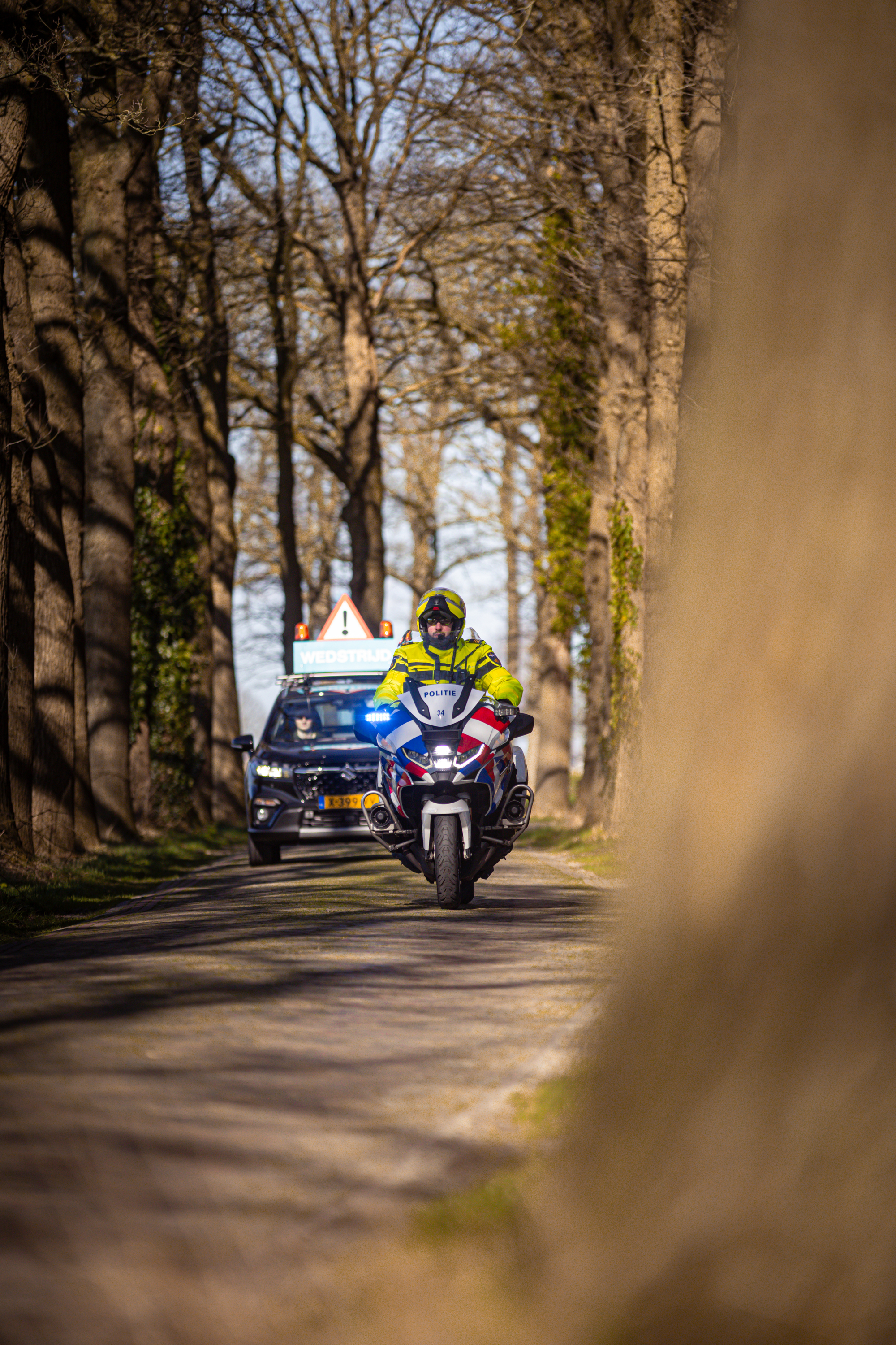 A motorcycle rider is on a road, with the word "Ster" visible in the background.