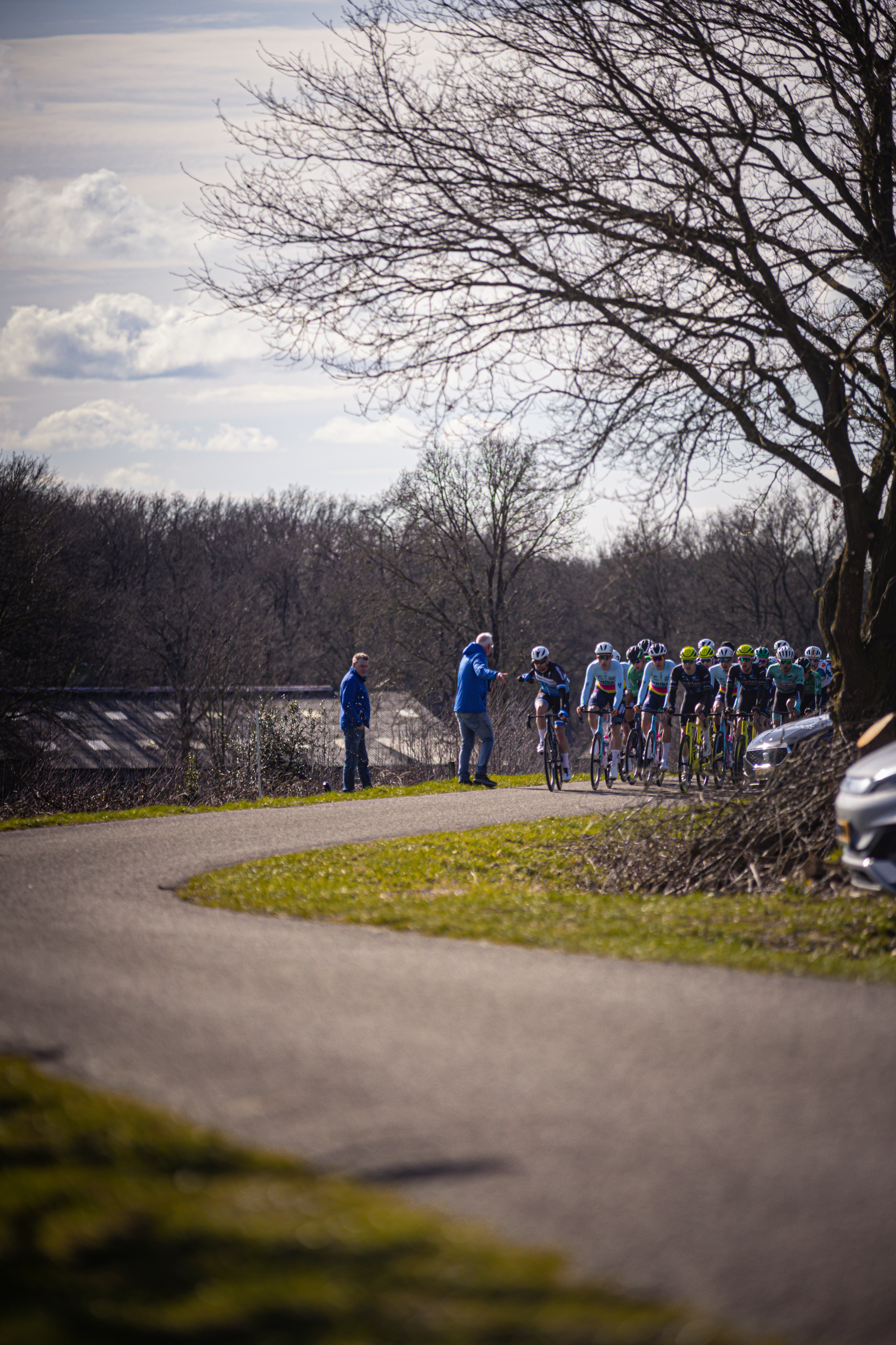 A group of cyclists on a road with a car next to them.