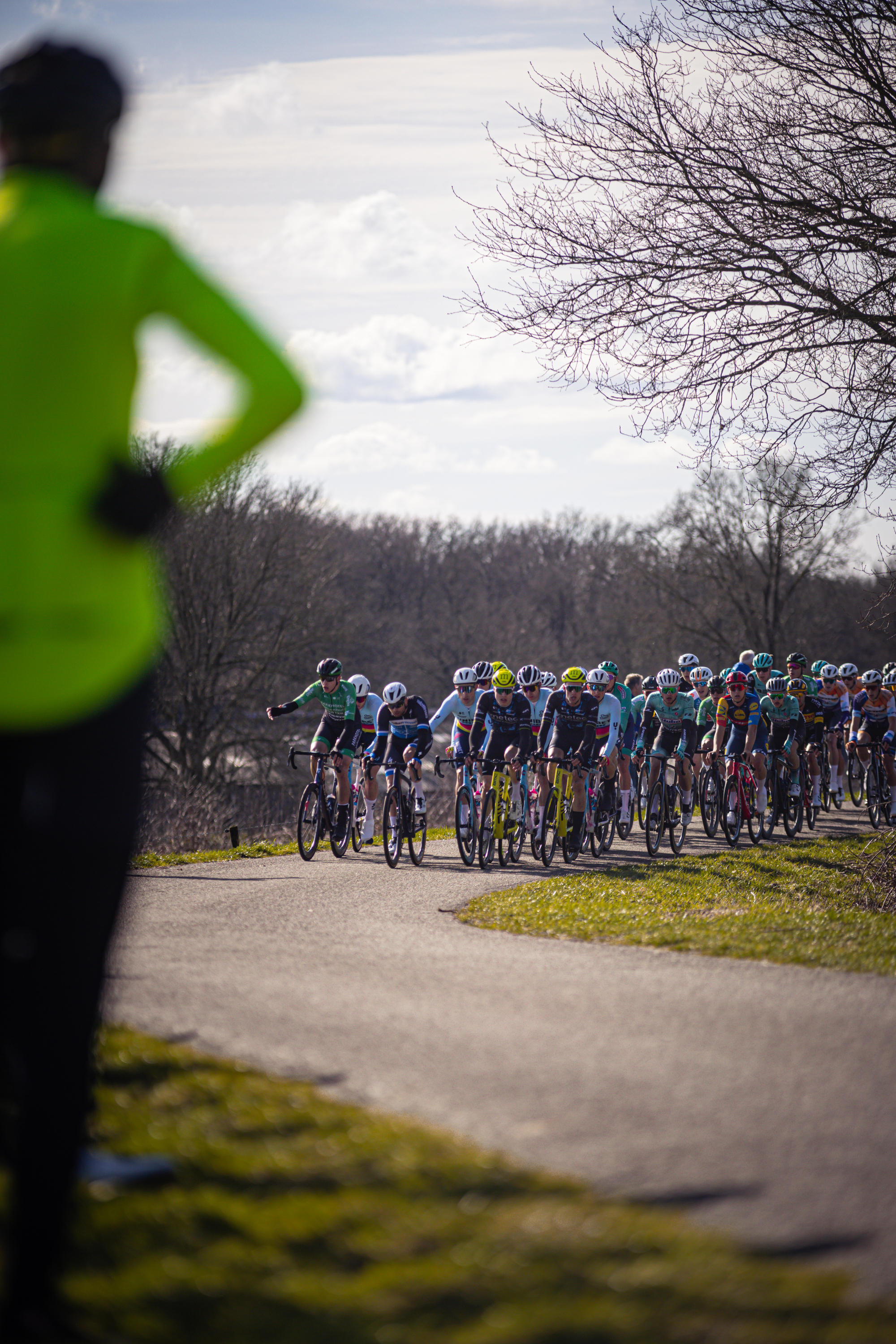 A group of bikers wearing colorful jerseys, all on their bikes. The bike in the center is blue and has a number 1 on it.