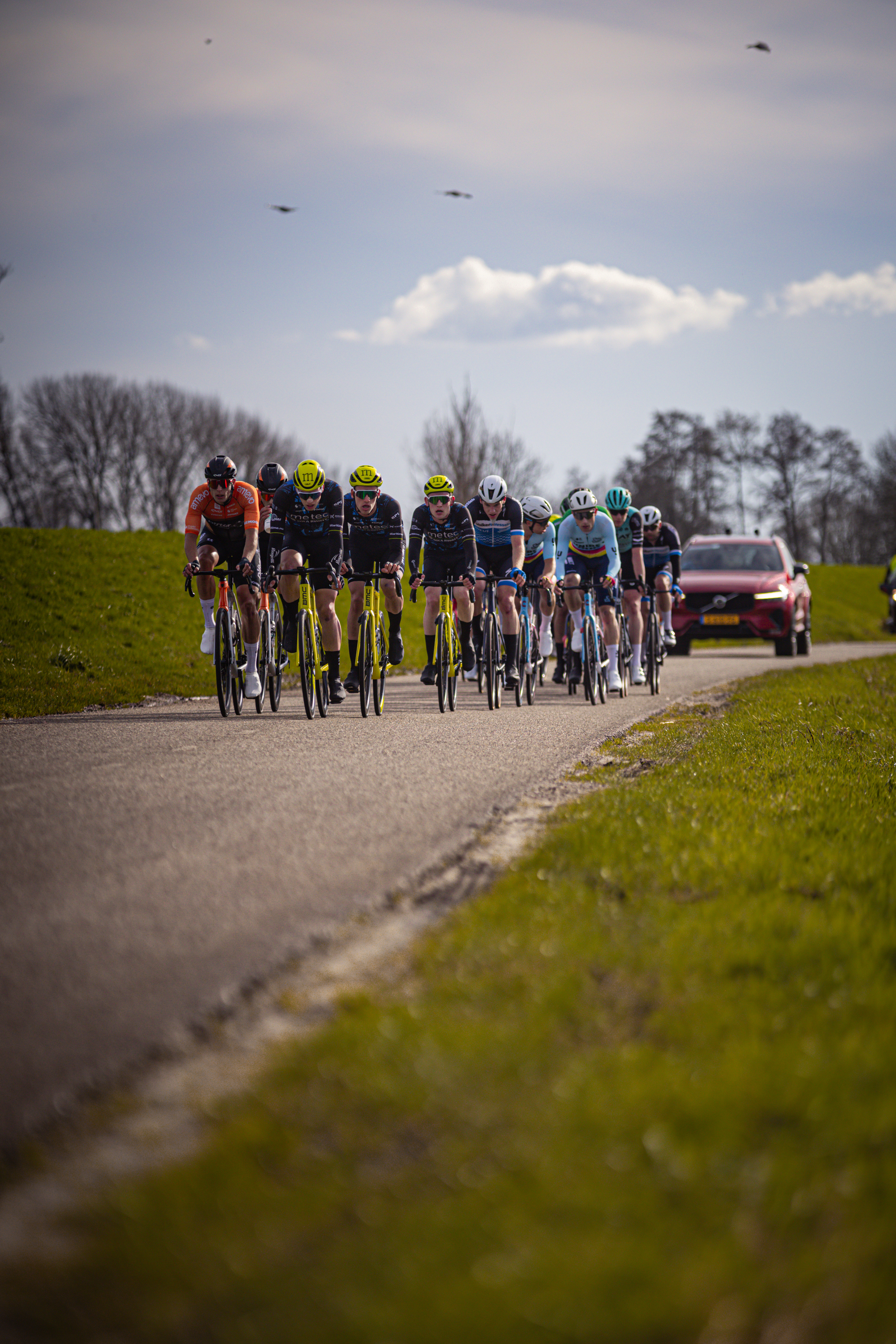 A group of cyclists wearing yellow helmets on a road that is near the Ster van Zwolle cycling event.