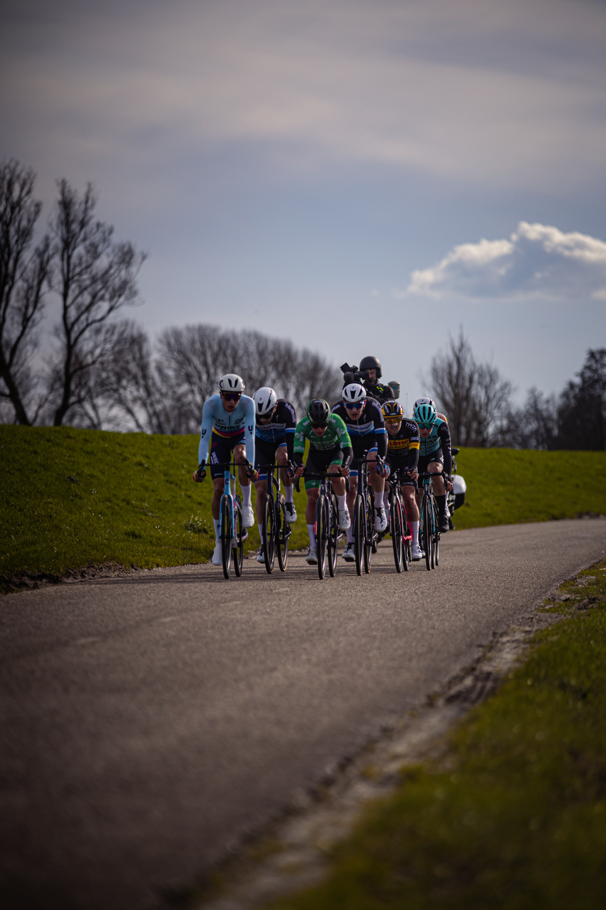 A group of cyclists, including number 4 and number 6, are participating in a race on a paved road.