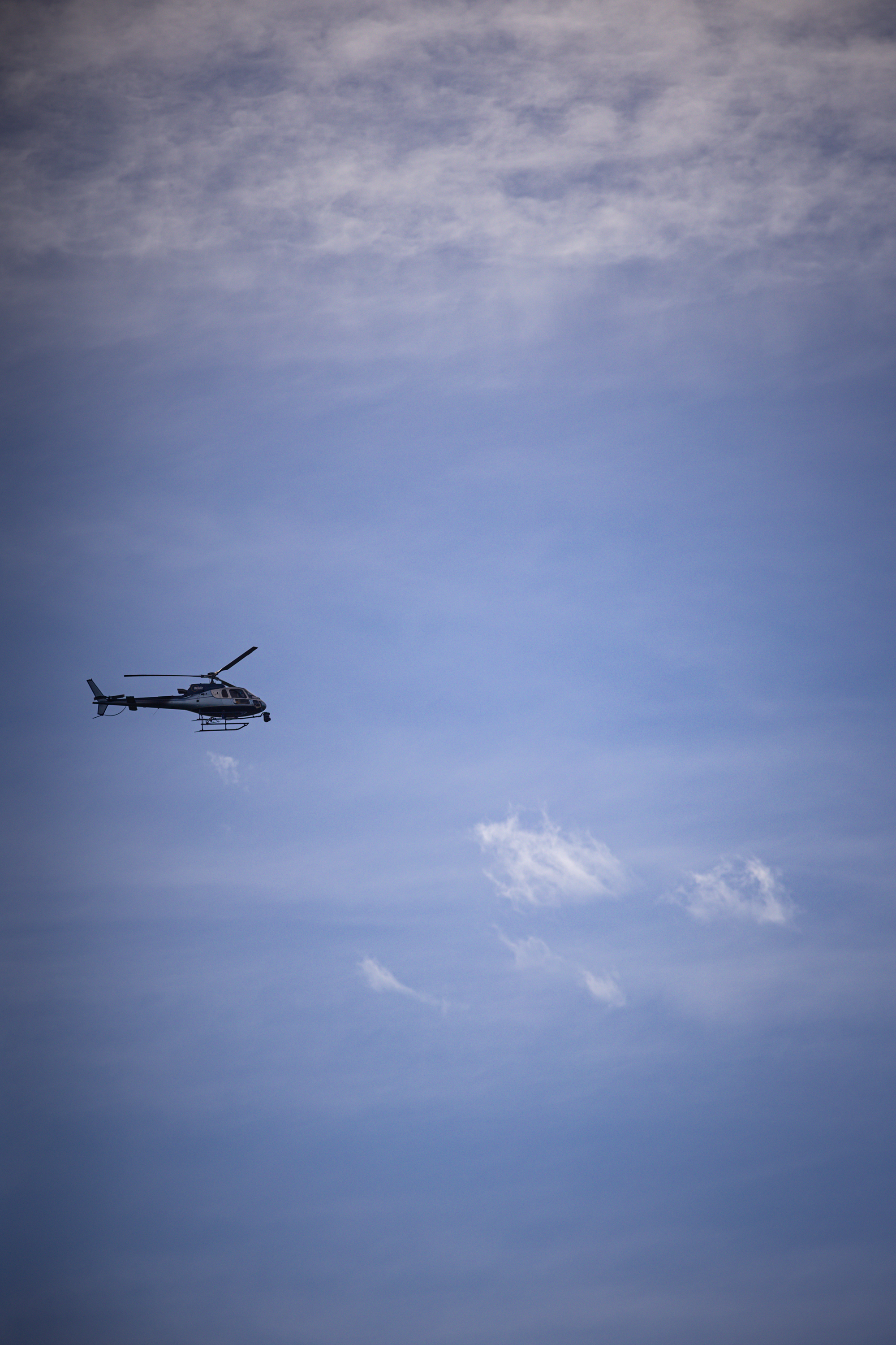 A helicopter in the air with a trail of smoke coming out.